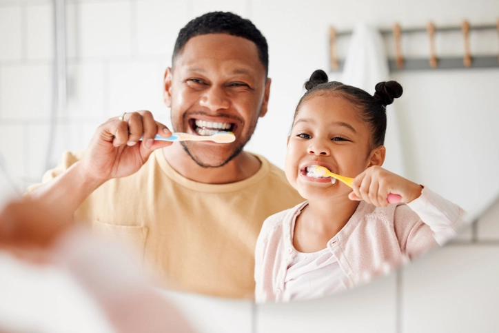dad and daughter brushing teeth together