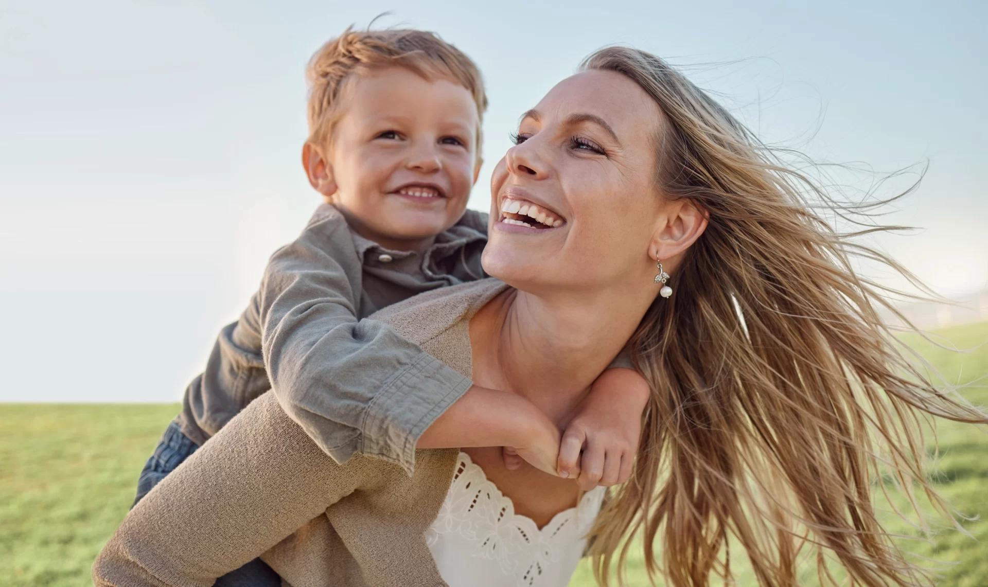 Woman carrying her son on her back with their beautiful smile