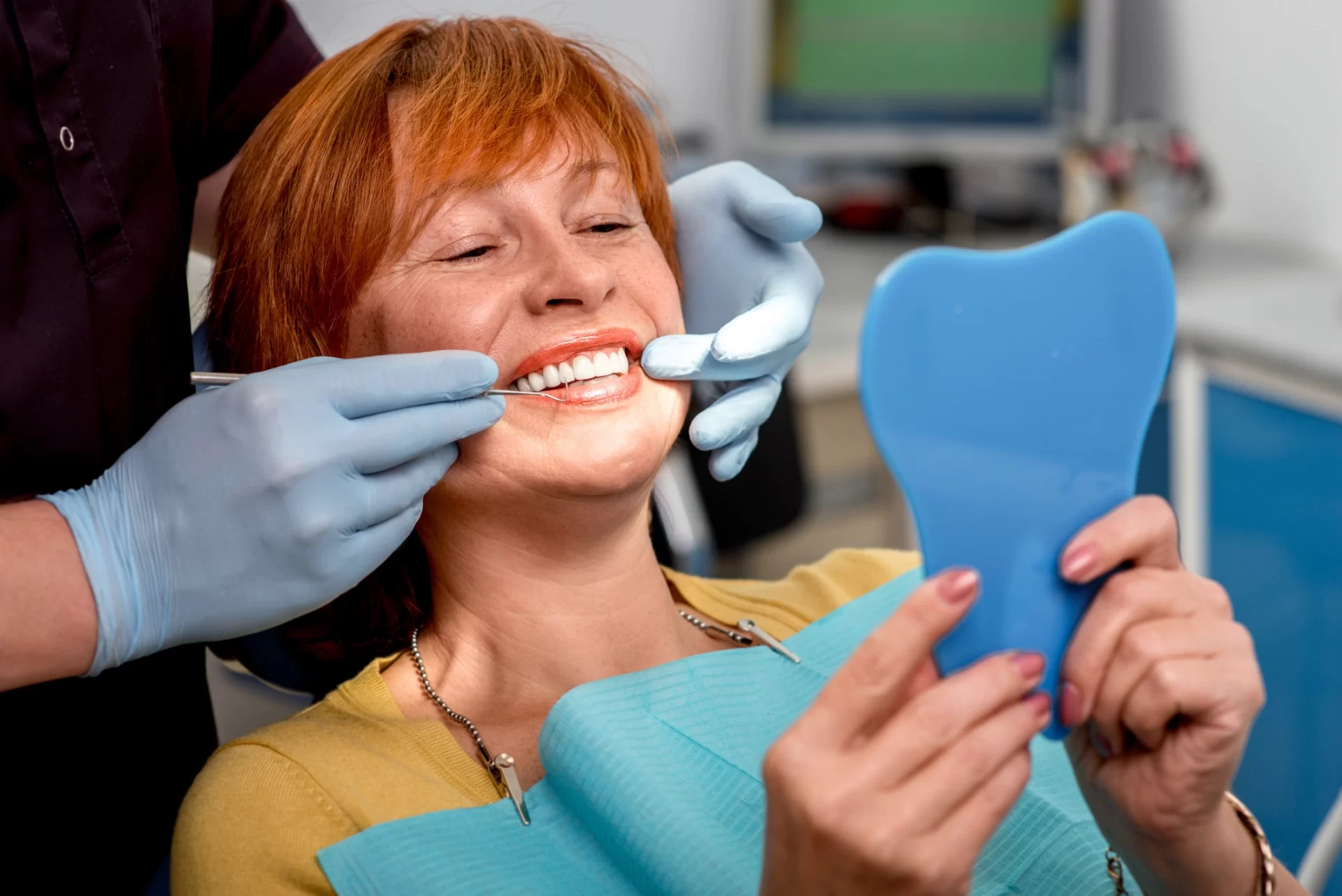 woman smiling in dentist chair holding a mirror